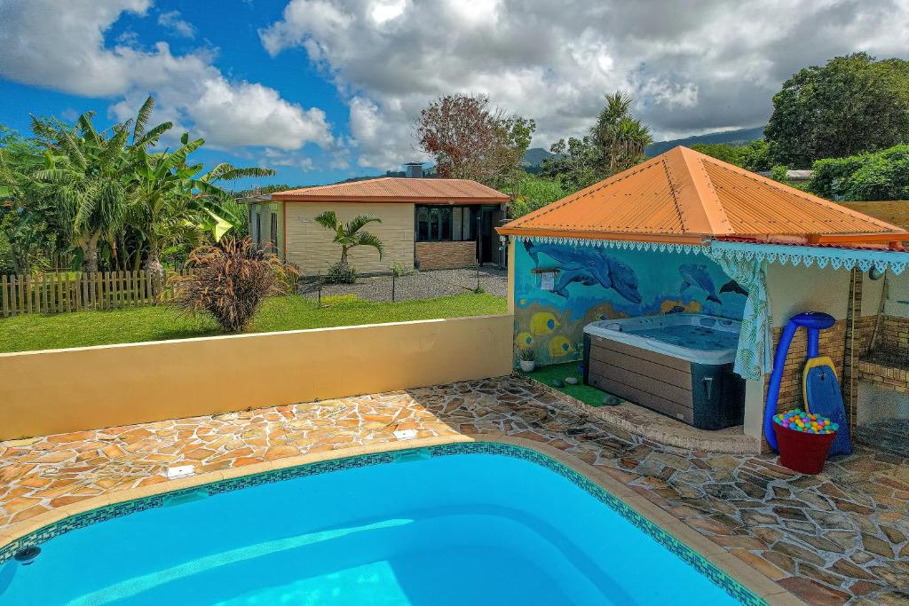 einen Pool mit einem Poolhaus mit einem Whirlpool in der Unterkunft GIGITE COCO in Saint-Joseph
