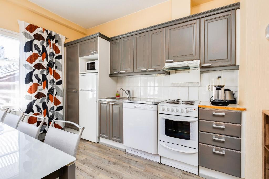 a kitchen with gray cabinets and white appliances at Levillenet Glacier Alpine Chalets at Levi Centre in Levi