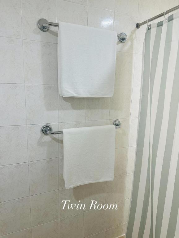 two white towels are hanging on a shower curtain at Surin Bay Inn in Surin Beach