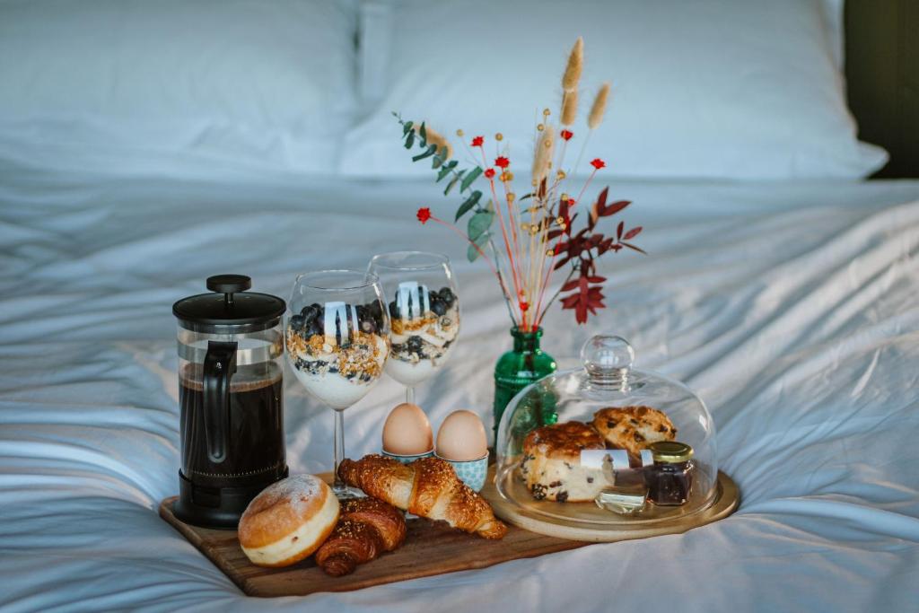 a tray of food and wine glasses on a bed at Wild Hideaways Luxury Lodges and Eco Spa in Bantry