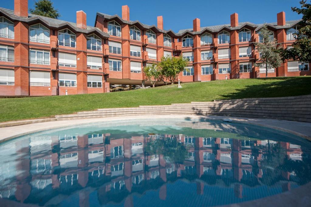 a building with a pool of water in front of it at elegante apartamento con parking y gym en urbanización de Lujo en Aravaca in Madrid