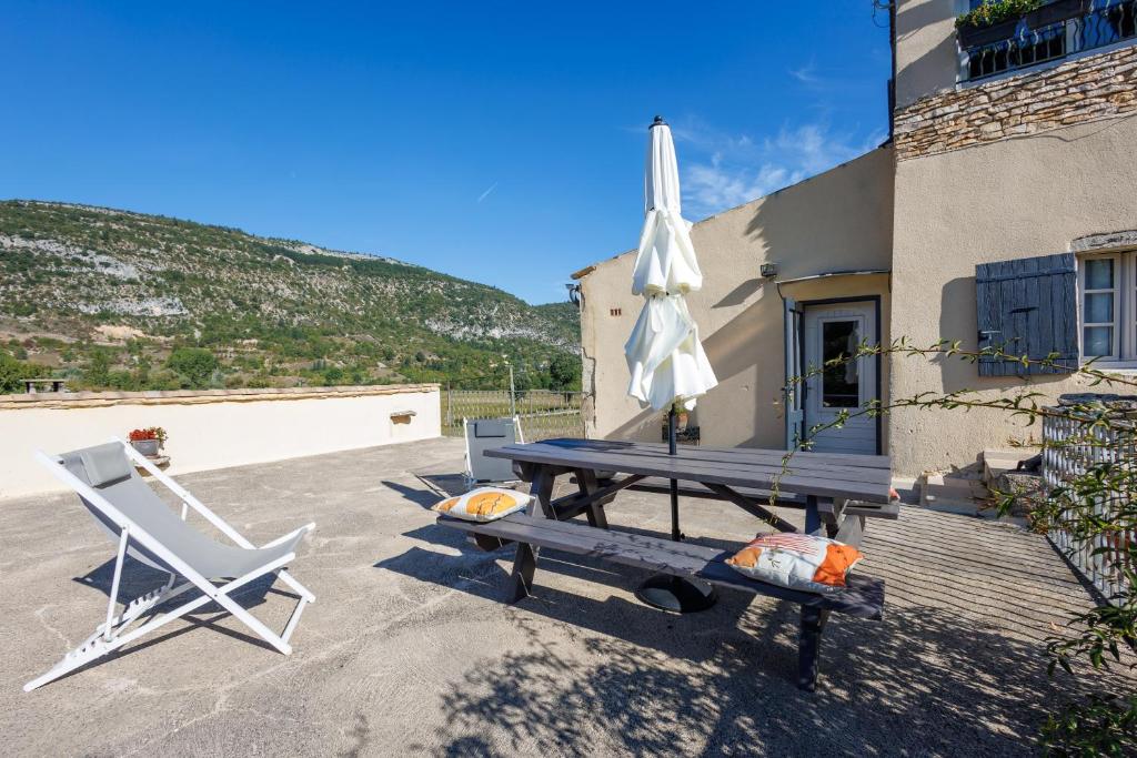 une table de pique-nique, une chaise, un parasol, une table et un banc dans l'établissement Le Viguier - Maison avec terrasse vue montagne, à Monieux