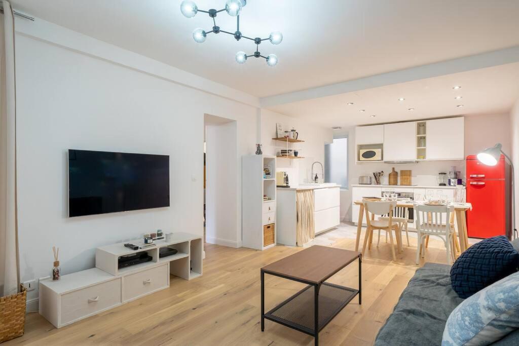 un salon avec un canapé et une télévision et une cuisine dans l'établissement RICHEBOURG à 5min du Jardin des plantes, à Nantes
