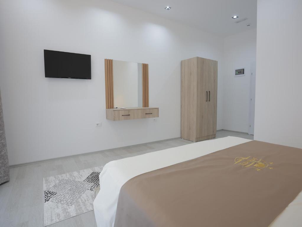 a white bedroom with a bed and a tv at Shatri Hotel in Vranisht