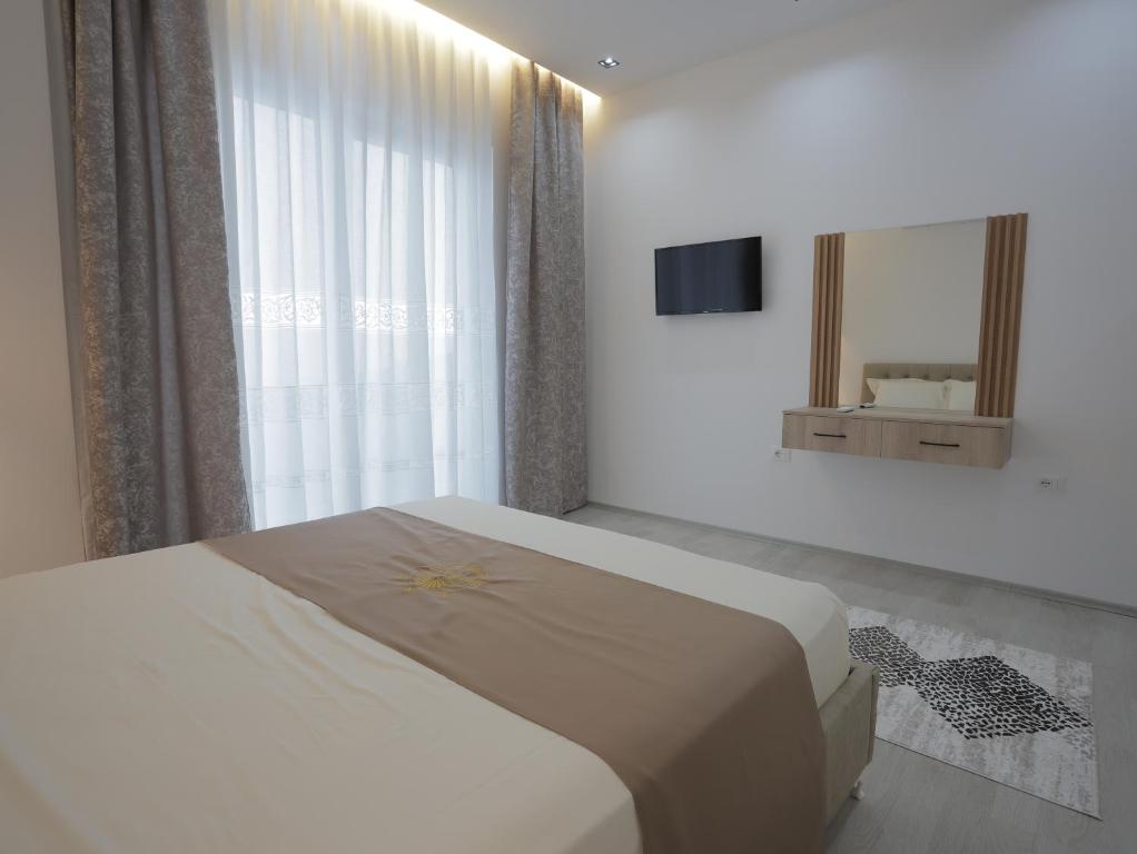 a white bedroom with a bed and a mirror at Shatri Hotel in Vranisht