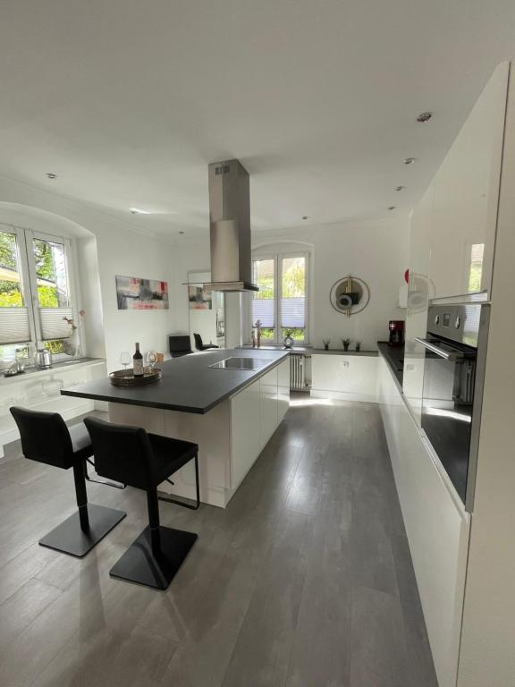 a kitchen with white cabinets and a black counter top at Ferienwohnung im alten Forstamt in Erndtebrück