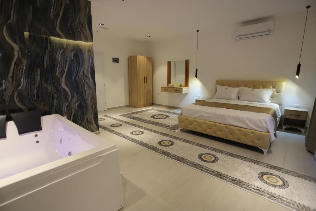 a bedroom with a bed and a tub and a sink at Shatri Hotel in Vranisht