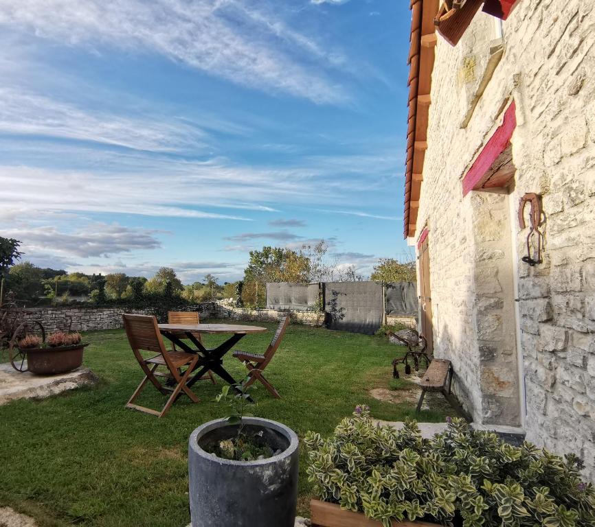 een terras met een tafel en stoelen in een tuin bij Épi Cottage in Coulgens