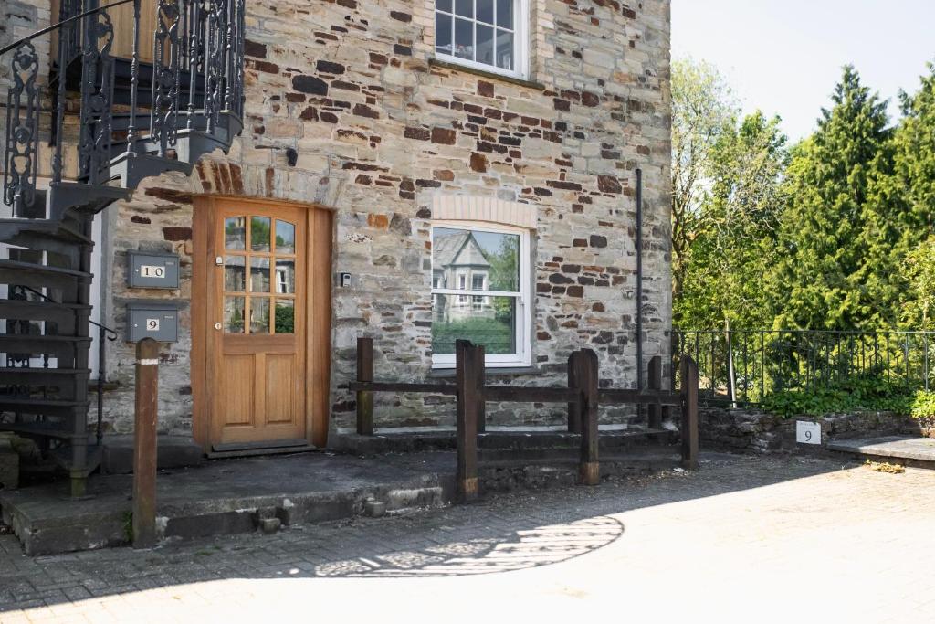 un edificio in mattoni con una porta in legno e una recinzione di No.9 Priory House, Bodmin a Bodmin