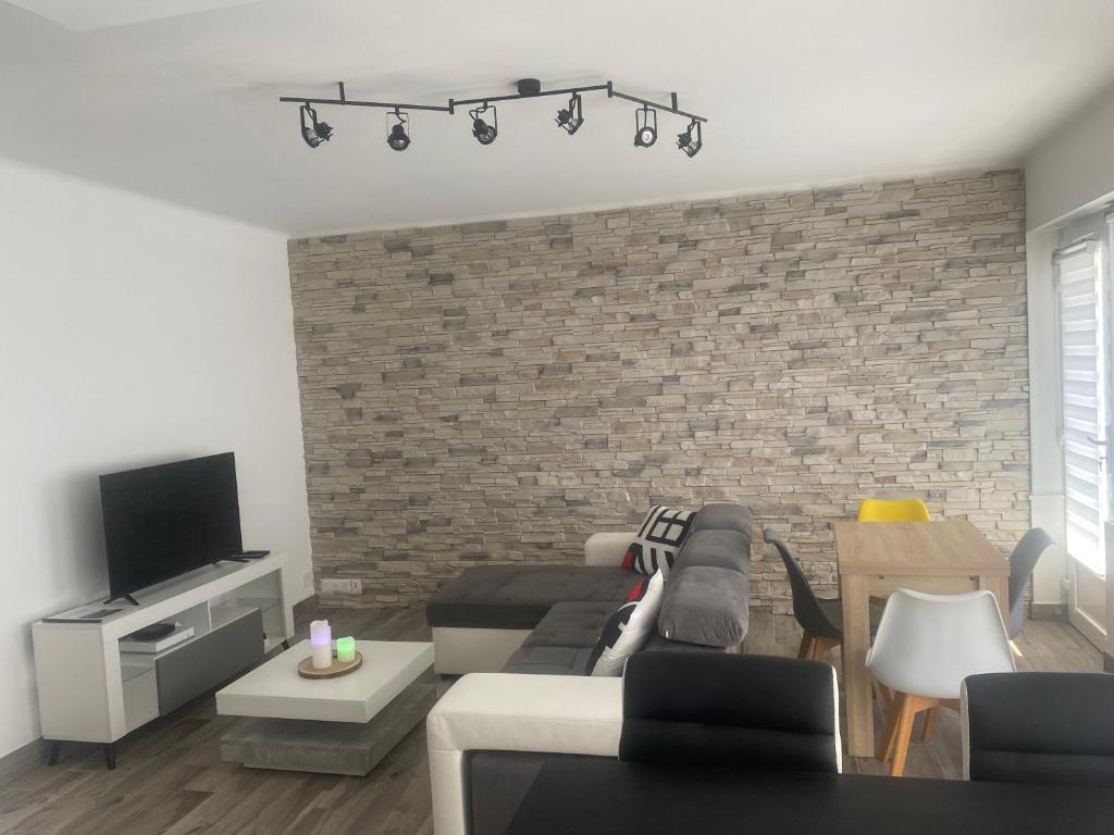 un salon avec un canapé et un mur de briques dans l'établissement Grand T2 tout équipé centre-ville, spacieux et lumineux, 1 chambre, 1 à 4 pers, possible 5 pers avec lit d'appoint pour 15 euros, climatisation, wifi, balcons, parking privé surveillé compris, à Lorient