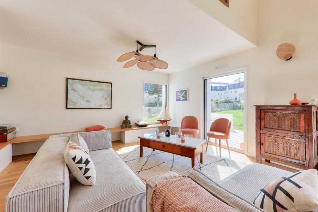 een woonkamer met een bank en een tafel bij À 300m de la plage, belle maison neuve in Sarzeau