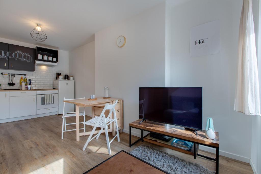 un salon avec une table et une grande télévision dans l'établissement Le petit Romo - Entre châteaux et Beauval, à Romorantin-Lanthenay