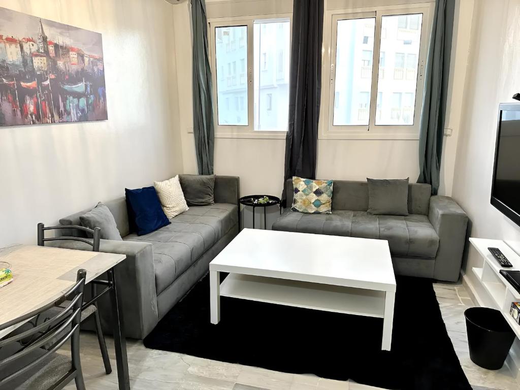 a living room with a couch and a table at Appartement cosy à 5 min de la plage Sidi Kacem in Hajreien