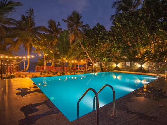 a swimming pool at night with lights around it at Frangipani Beach Villa in Tangalle