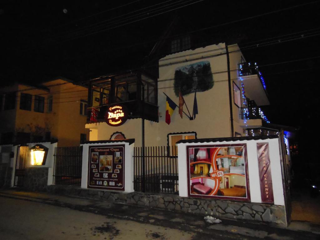 un bâtiment avec des affiches sur son côté la nuit dans l'établissement Pensiunea Dapa, à Predeal