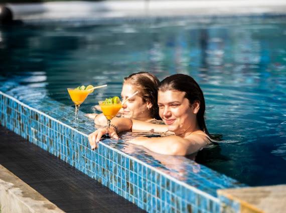 a man and woman in a swimming pool with drinks at Frangipani Beach Villa in Tangalle