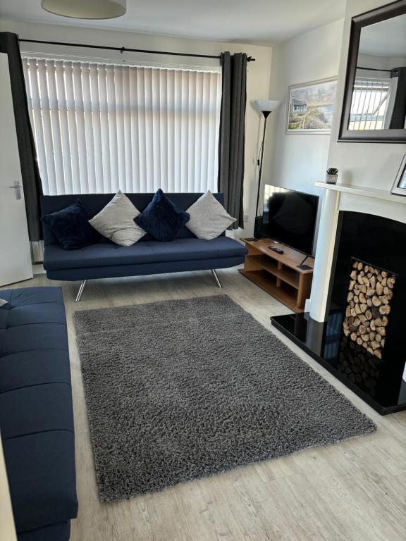 a living room with a blue couch and a fireplace at Stylish 3 bedroom house in Whitchurch