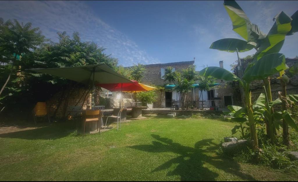 une cour avec des chaises et des parasols et une maison dans l'établissement Les chambres du Nid charentais, à La Poterie