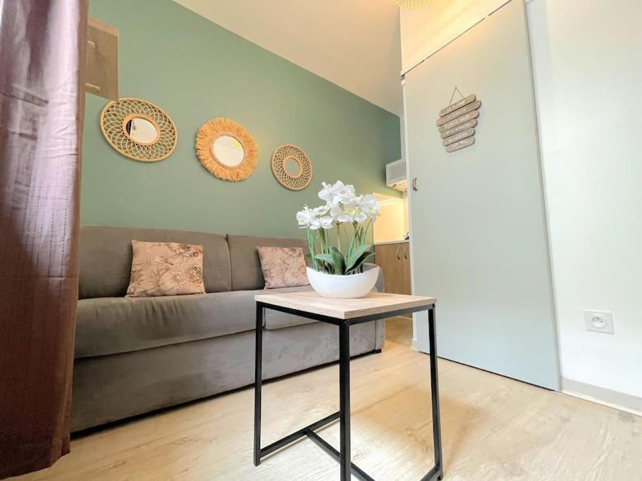 a living room with a couch and a table with flowers at Mini studio 10m2 central & clim Idéal pour une escale à Béziers in Béziers