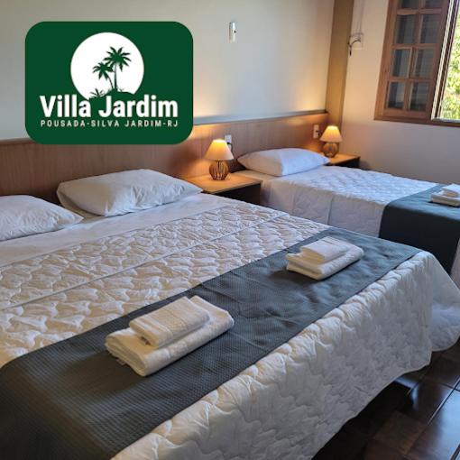 two beds in a hotel room with towels on them at Pousada Villa Jardim in Silva Jardim