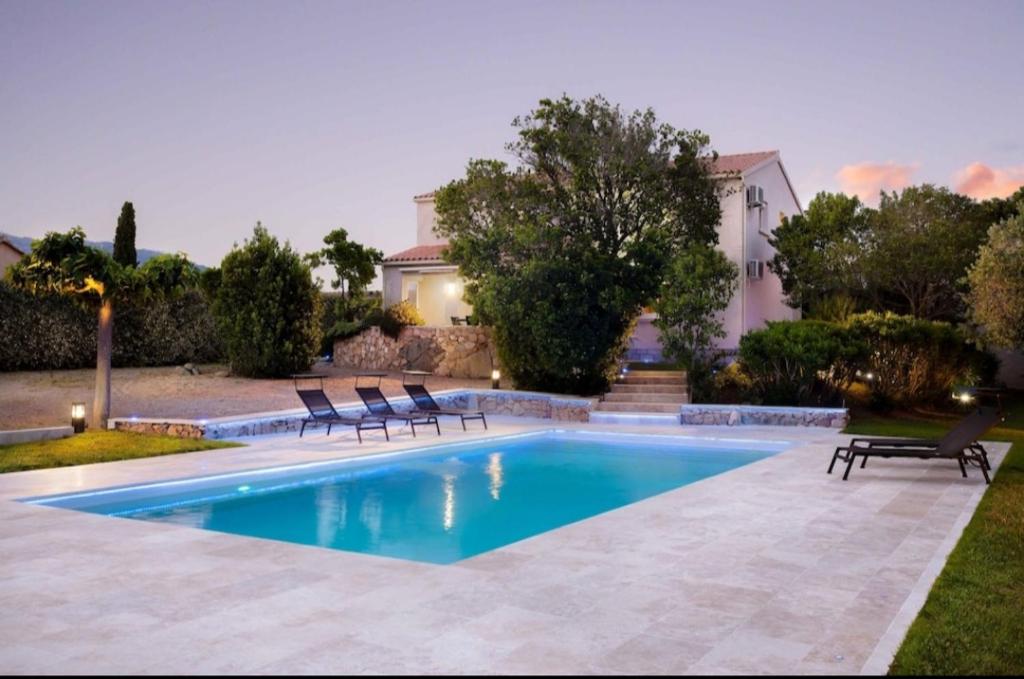 une piscine avec deux chaises et une maison dans l'établissement VILLA Pauline, à Porto-Vecchio