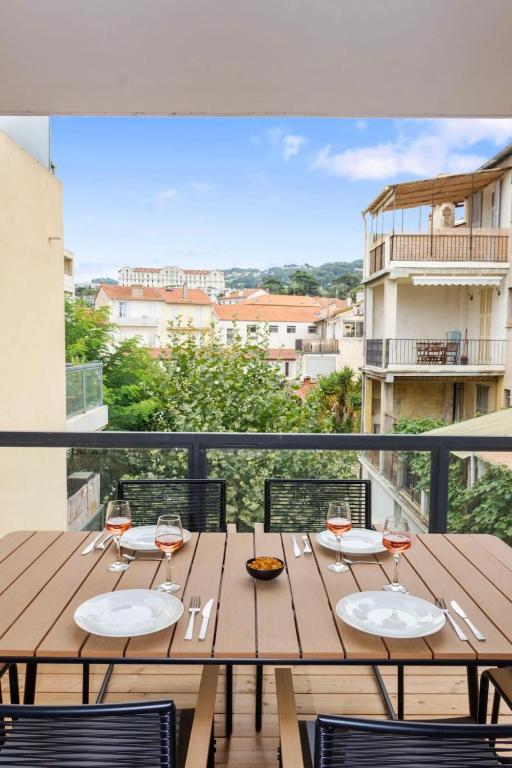 - une table en bois avec des verres à vin sur le balcon dans l'établissement Le Prince - Quiet - Parking - Hypercenter - AC, à Cannes
