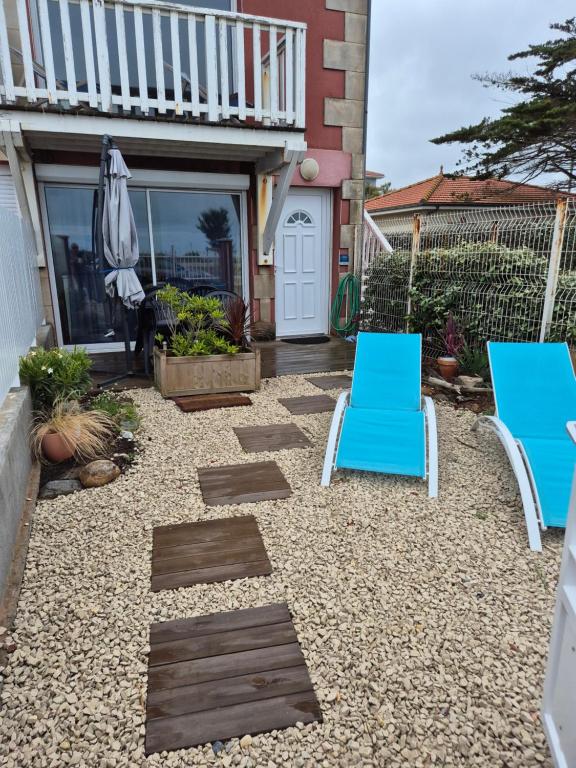 a patio with two chairs and an umbrella at Soulac Côté Plage - Devant l'océan in Soulac-sur-Mer