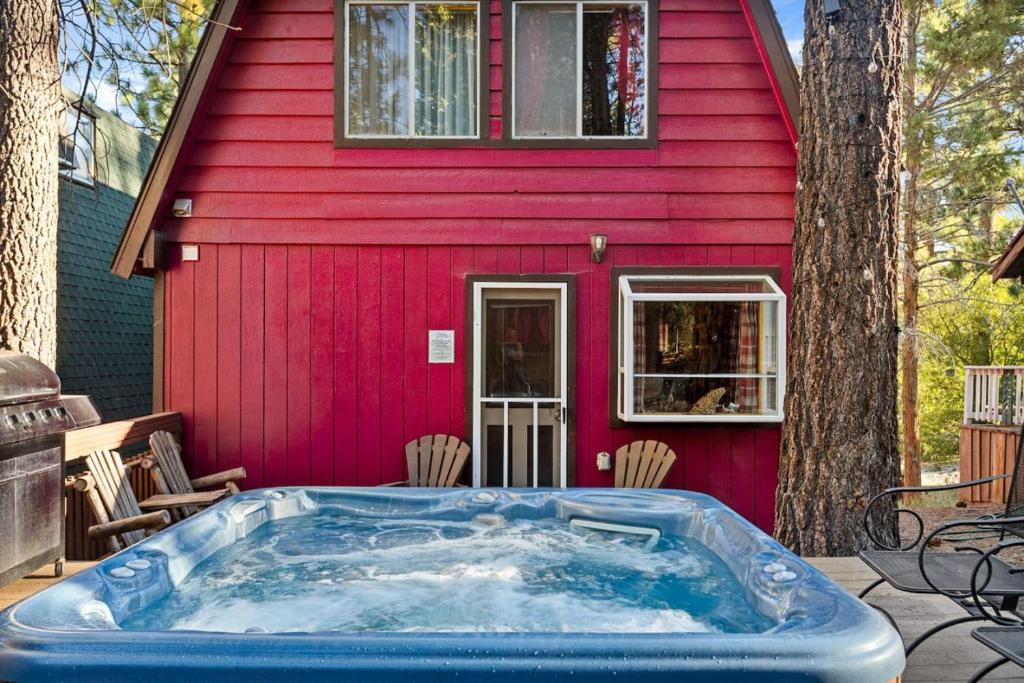 a hot tub in front of a red house at The Lions Den in Big Bear City