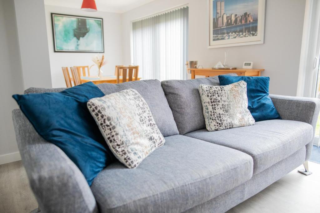 a gray couch with blue pillows in a living room at Lovely 3 Bedroom House in Chelmsford in Chelmsford
