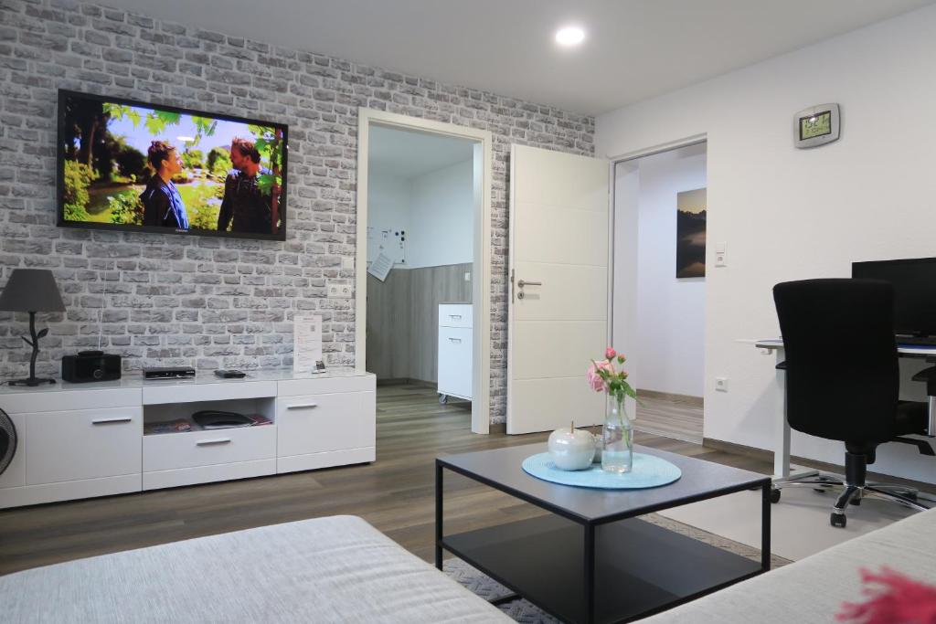 un salon avec une télévision sur un mur en briques dans l'établissement Ferienwohnung Loh - 55Zoll TV - Schnelles Internet 500MBit, à Schwäbisch Hall