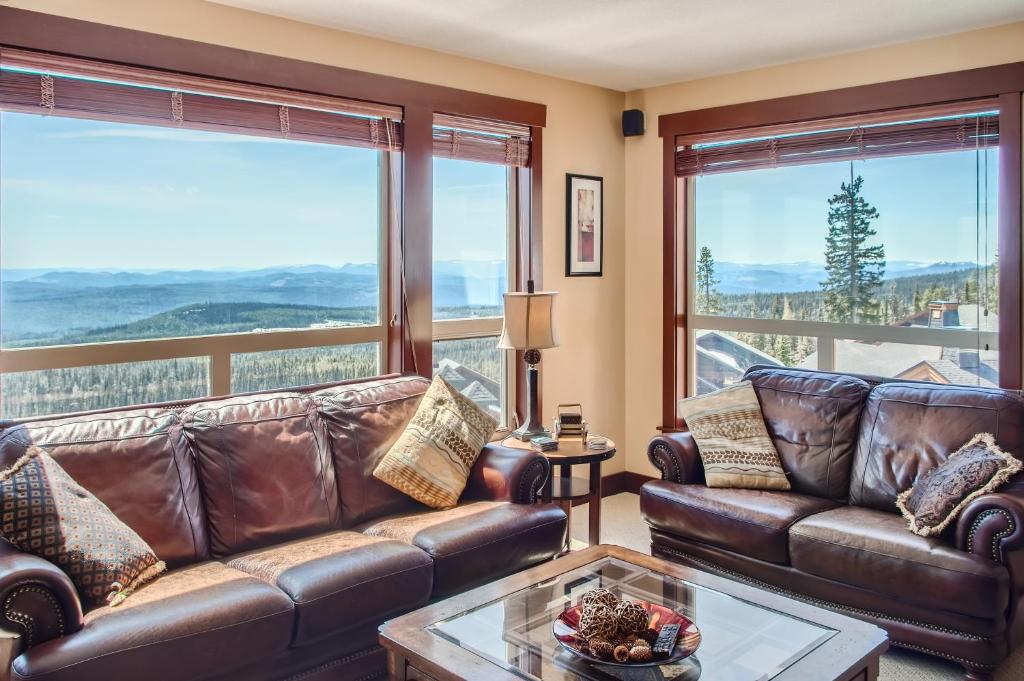 a living room with leather furniture and large windows at Stonegate Resort Unit C304 in Big White