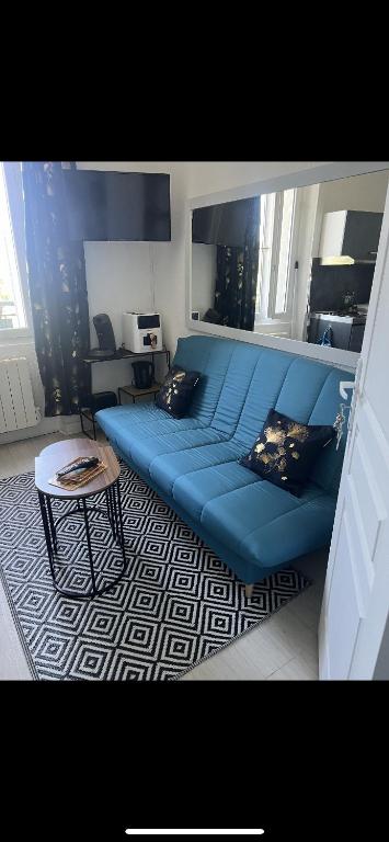un canapé bleu dans un salon avec une table dans l'établissement Appartement cosy proche gare, à Angoulême