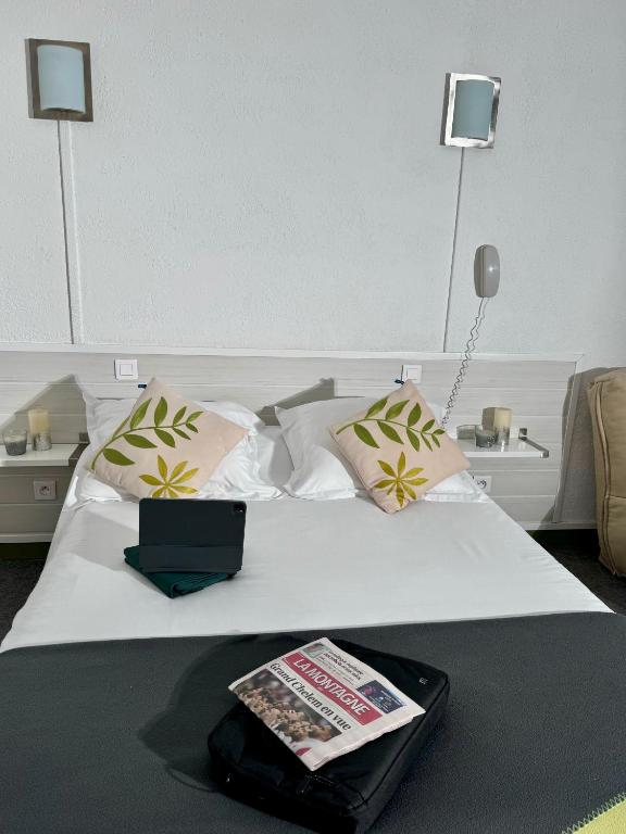 une chambre d'hôtel avec un lit avec un livre dessus dans l'établissement HOTEL De La Tour Saint Etienne SUD, à Saint Etienne