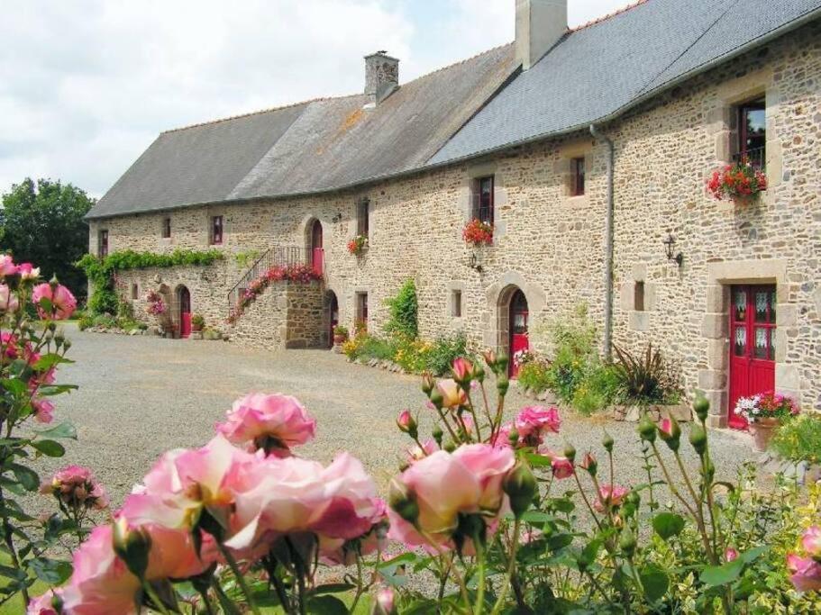 un bâtiment en pierre avec des fleurs devant lui dans l'établissement Le Manoir du Conquérant - Baie du Mont-St-Michel, à Baguer-Pican