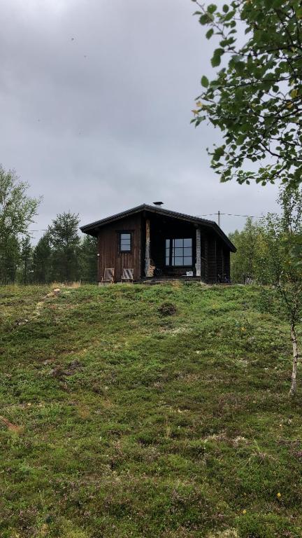 una vecchia casa su una collina con un prato di Kaamasmukka 77 a Koikkiniva