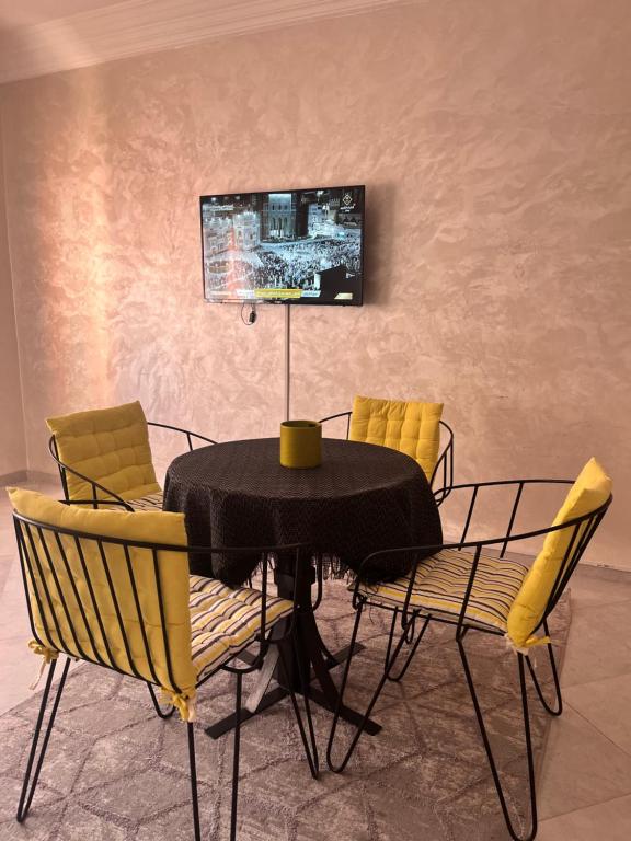 une table à manger avec des chaises et une télévision murale. dans l'établissement La rose à côté Carry, à Marrakech