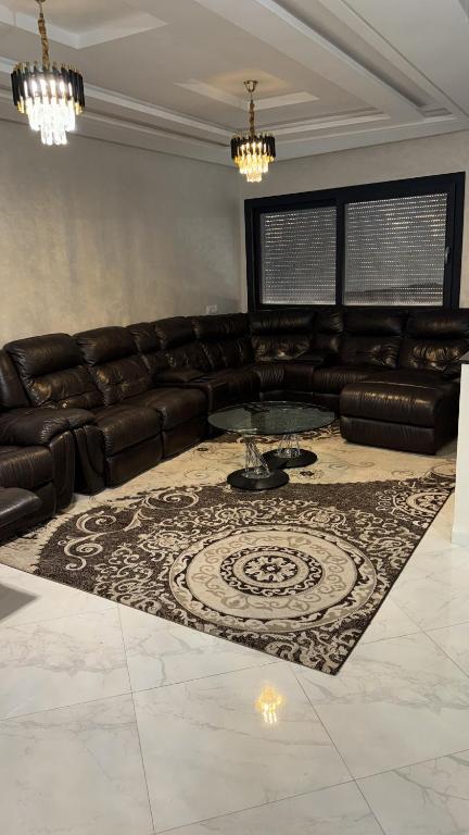 a living room with a leather couch and a table at Founty Agadir near the beach in Agadir
