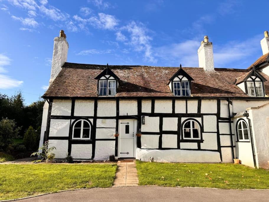une ancienne maison noire et blanche avec une allée. dans l'établissement Stylish Tudor Cottage & Hot Tub, à Coombe Hill