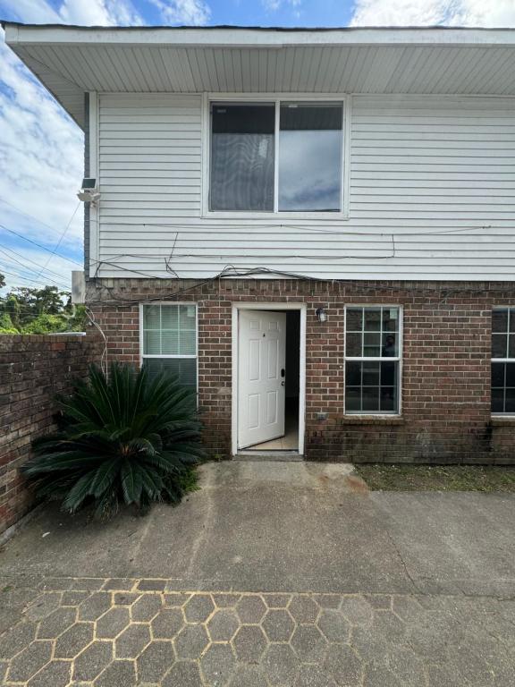 a brick house with a white door and a driveway at Cozy 2-Bedroom in Harvey