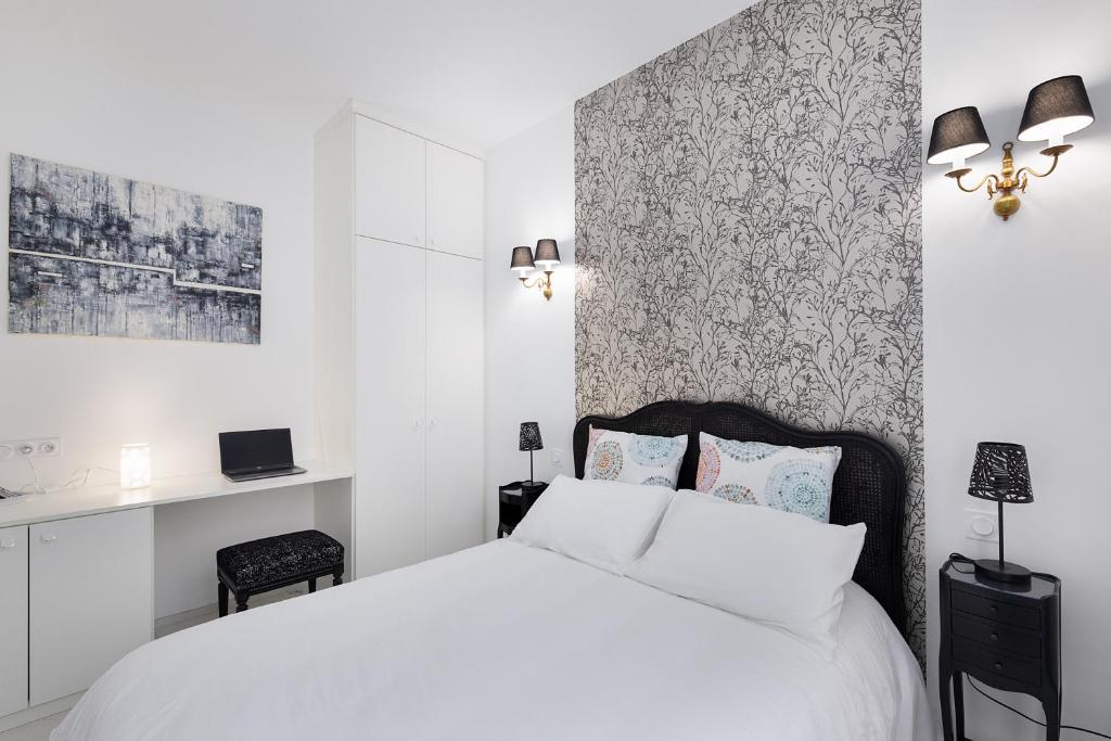 Hotel Les Montgolfières, 2 Pièces, Porte de Versailles, a bedroom with a white bed and a wall at Les Montgolfières, 2 Pièces, Porte de Versailles in Paris