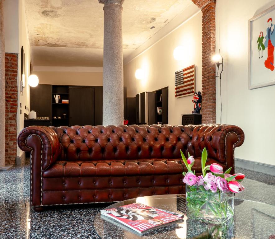 a brown leather couch in a living room with a table at Luxury Loft near Duomo and Garage in Milan