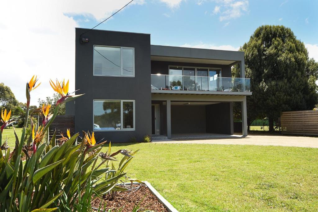 a black house with a balcony in a yard at Rolling Waves in Pt Leo in Shoreham