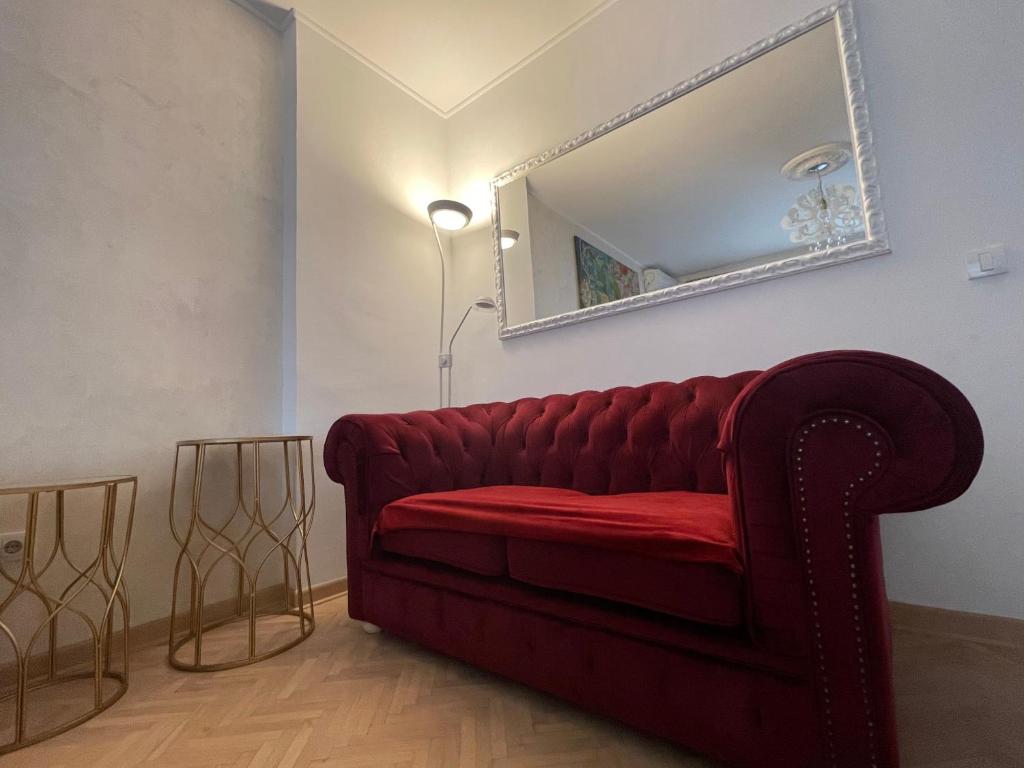 a red couch in a living room with a mirror at Dreamscape City Center in Belgrade