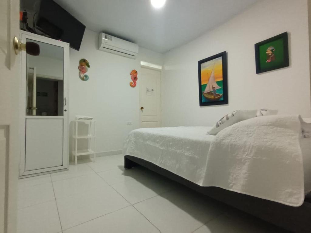 Un dormitorio blanco con una cama y un baño. en Hospedaje Belleza Isleña, en San Andrés
