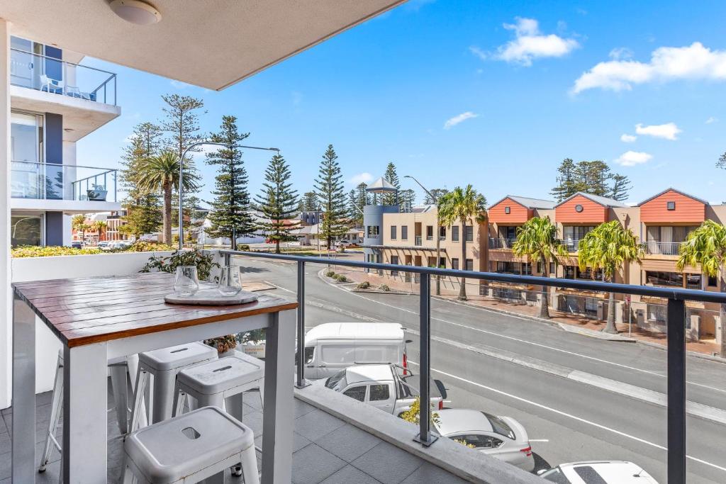 ein Balkon mit Tisch und Stühlen und eine Straße in der Unterkunft Kiama Sea Breeze Apartment in Kiama