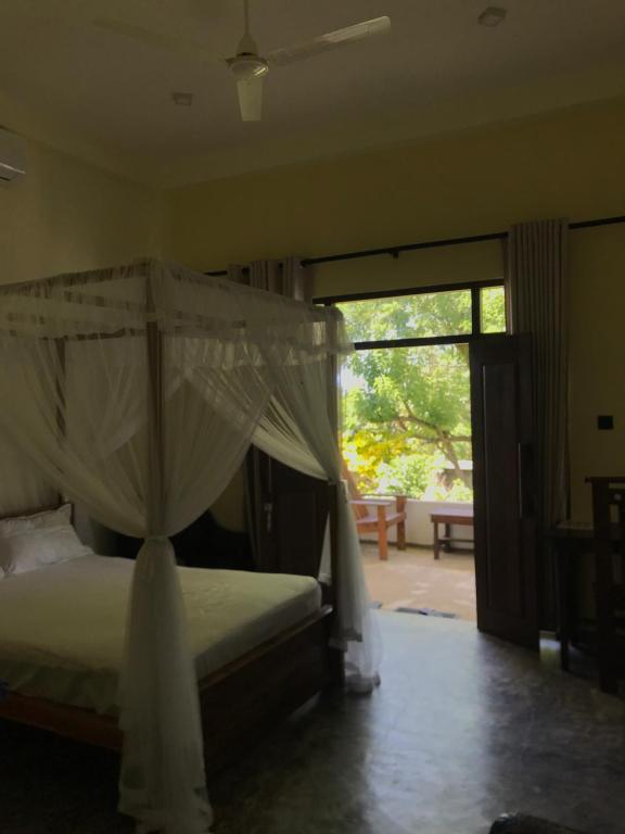 1 dormitorio con cama con dosel y puerta corredera de cristal en villa Wind, en Unawatuna