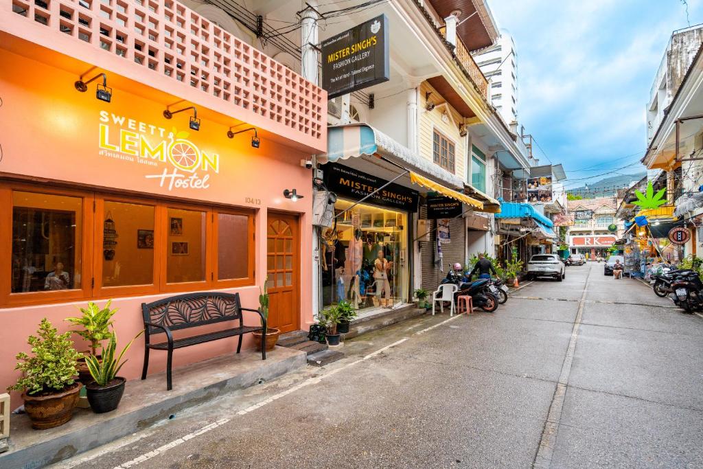 a city street with shops and a bench on the sidewalk at Sweett Lemon Hostel in Patong Beach
