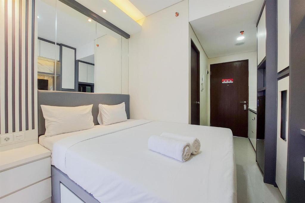 a bedroom with a white bed with a towel on it at Homey and Nice Studio at Transpark Bintaro Apartment By Travelio in Tangerang