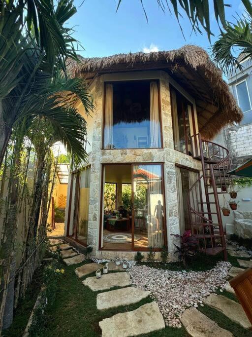 a small house with a thatch roof and a pathway at Jungle Circle Uluwatu in Uluwatu