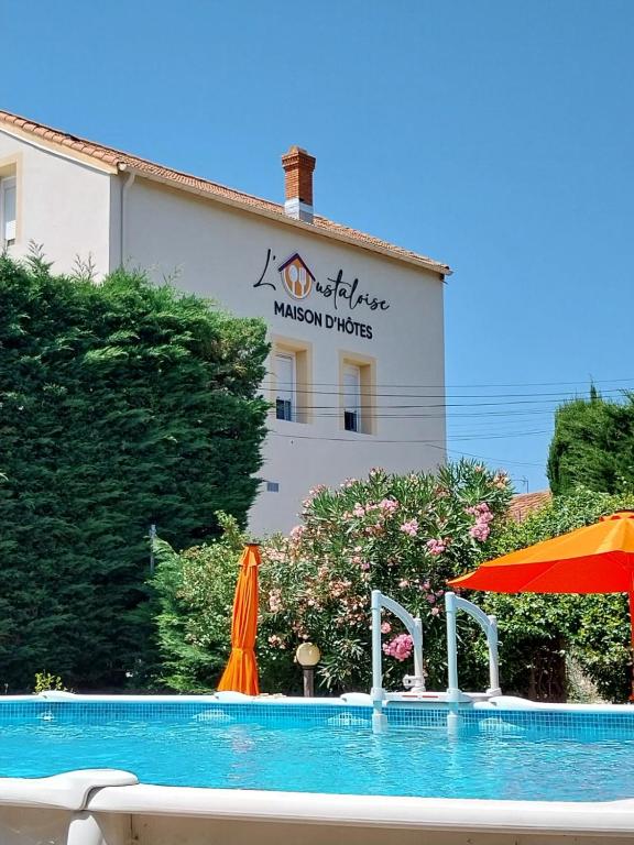 une piscine devant un hôtel dans l'établissement L'Oustaloise, à Faugères